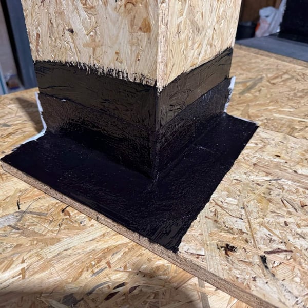 Abgedichtete Außenecke einer OSB-Holzkonstruktion mit schwarzem Flüssigkunststoff