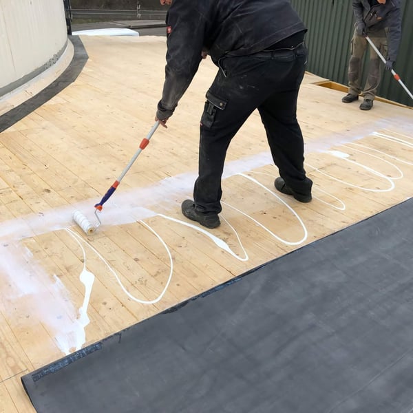 Auftragen des EPDM-Flächenklebers mit der Farbrolle auf die Holzschalung
