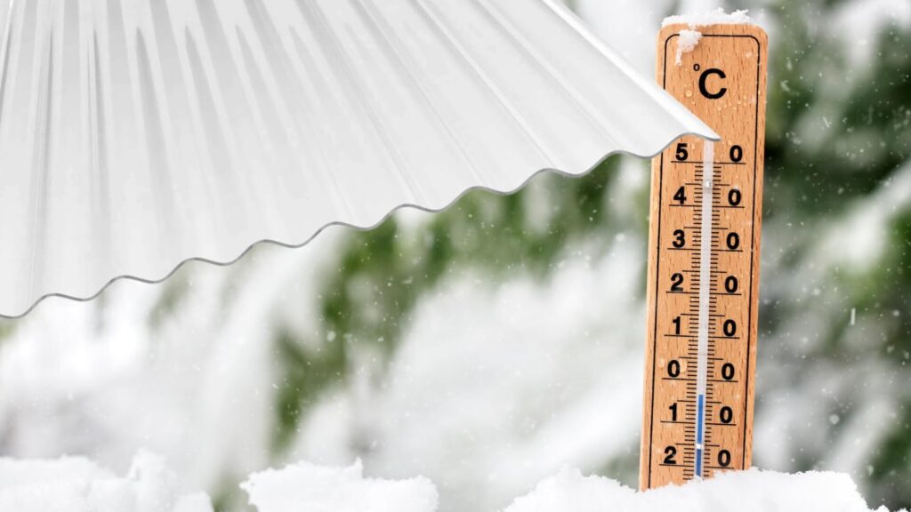Thermometer zeigt Kälte neben Lichtplatten auf verschneitem Dach, Wintertemperaturen