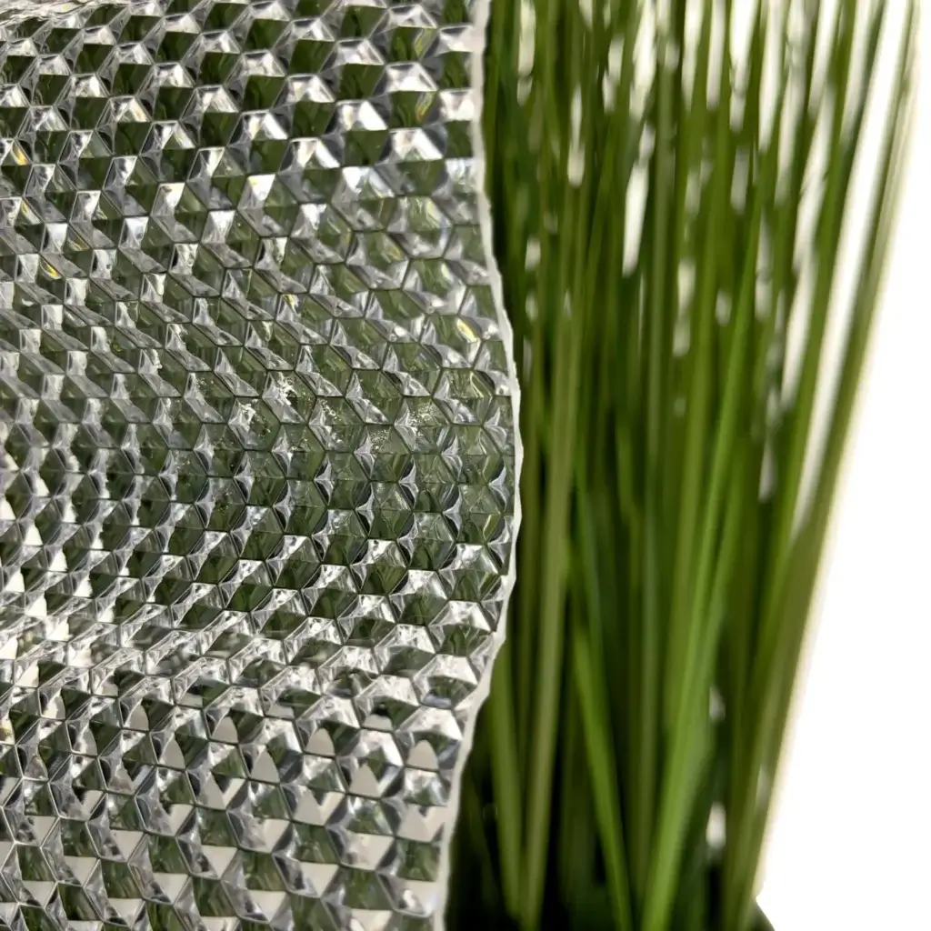 Detailaufnahme von Lichtplatten mit Wabenstruktur neben grünen Pflanzenblättern.