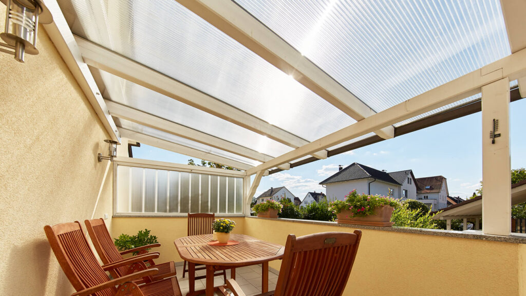 Sonnendurchflutete Terrasse mit Stegplatten-Dach, Holzmöbeln und Pflanzendekoration