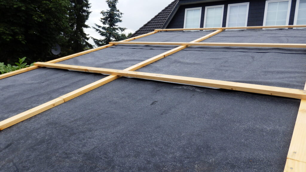Dachkonstruktion mit Holzlatten und schwarzer Unterdeckbahn im Aufbau