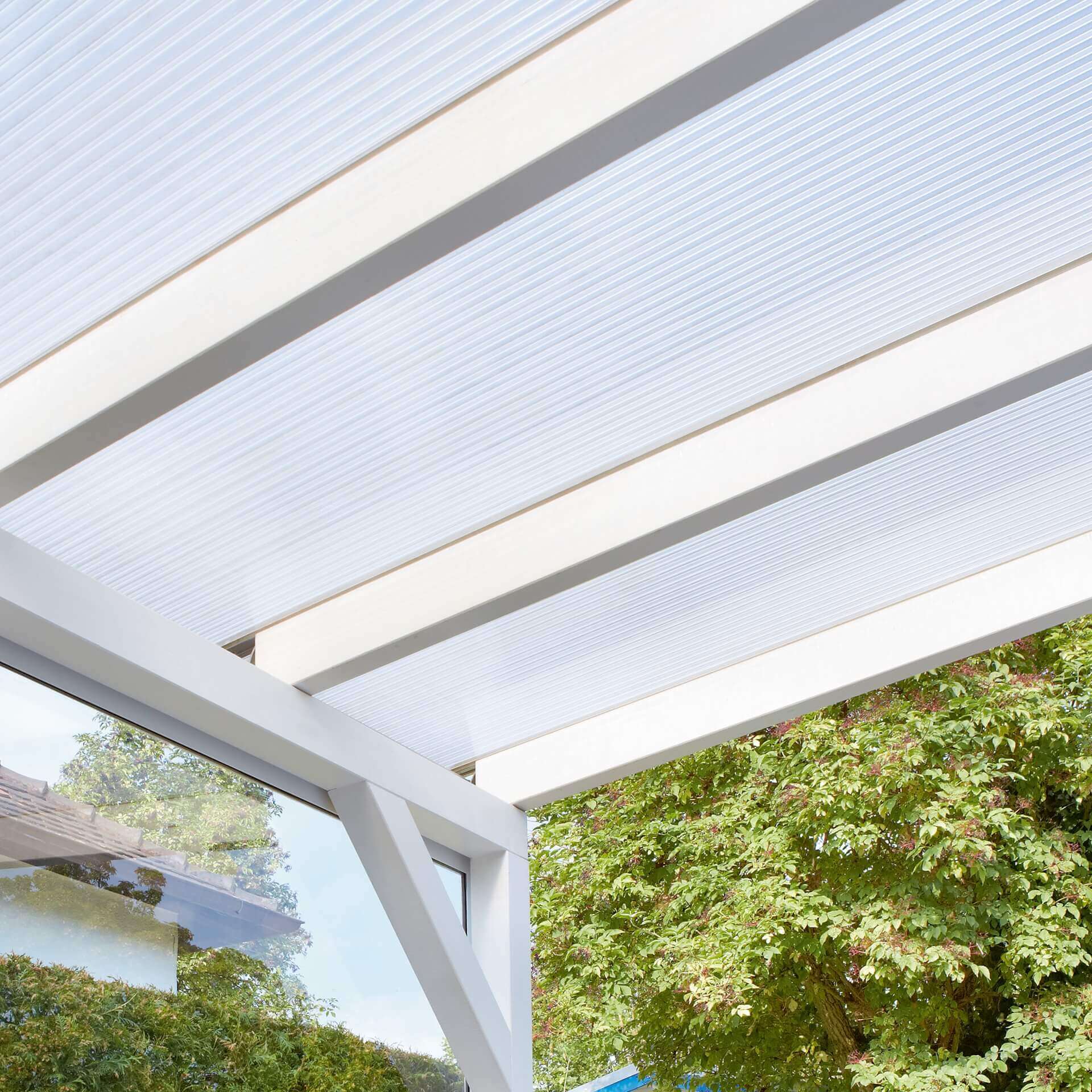 Das Bild zeigt eine Terrassenüberdachung mit Stegplatten. 
Die Unterkonstruktion ist weiß., die Stegplatten klar. 