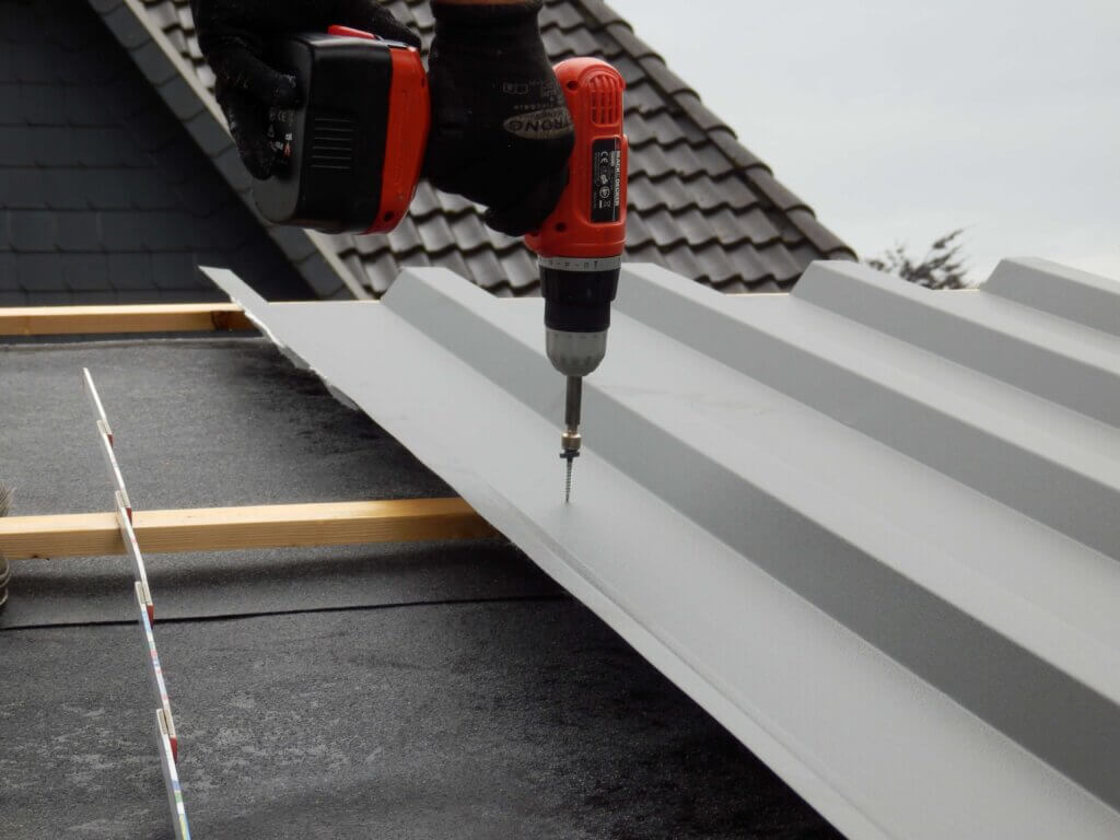 Montage eines hellgrauen Trapezblech mit Hilfe einer Bohrmaschine.