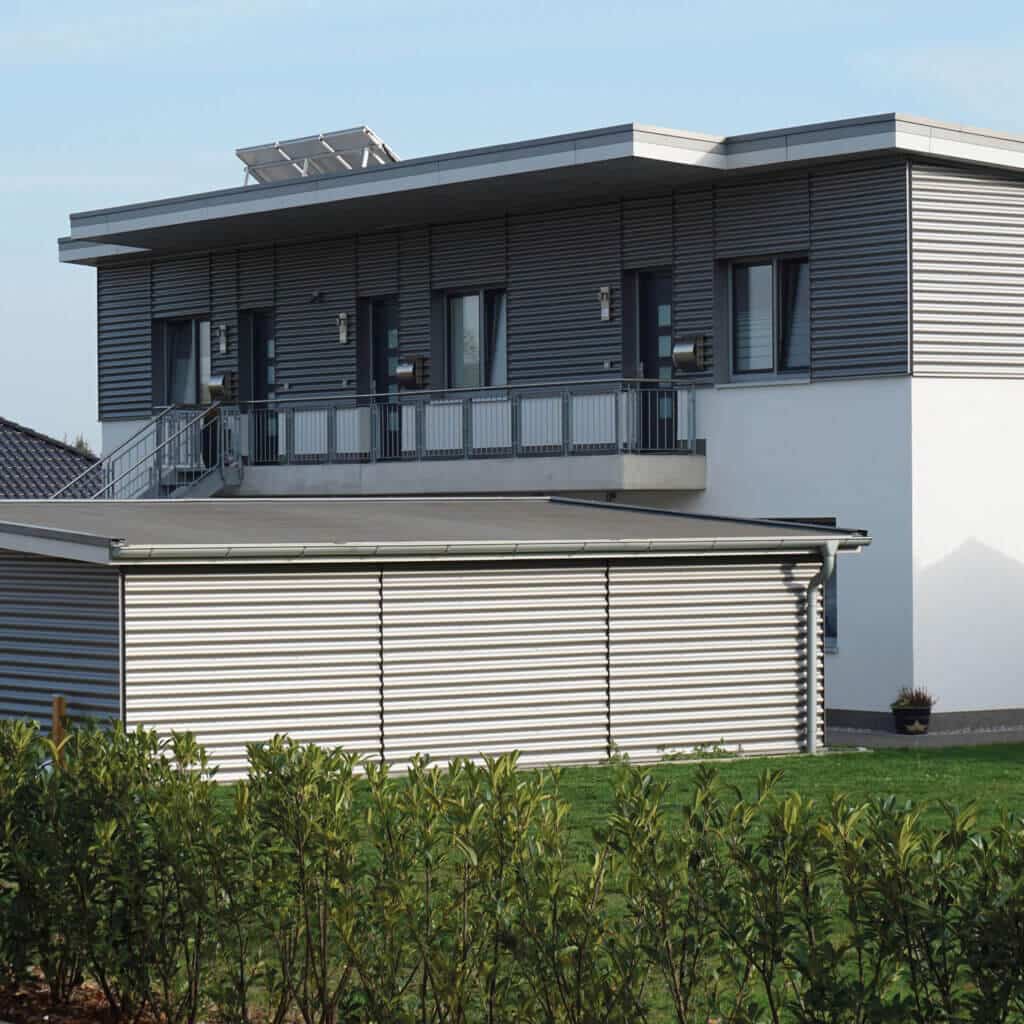 Das Bild zeigt ein Wohnhaus samt Carport mit einer Fassadenverkleidung aus Wellblech.