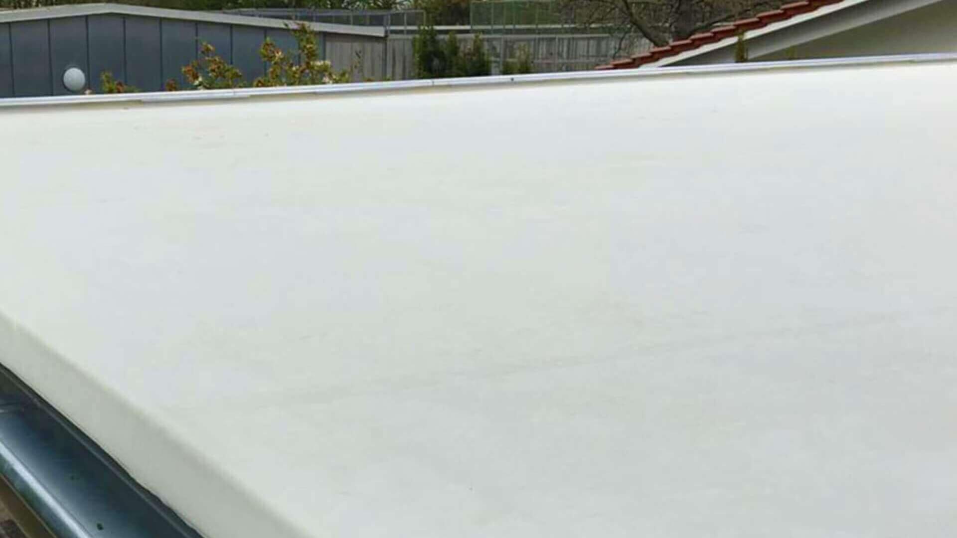 Flachdach mit sauber verlegter weißer EPDM-Dachfolie, kombiniert mit einer stabilen Regenrinne zur Wasserableitung.
