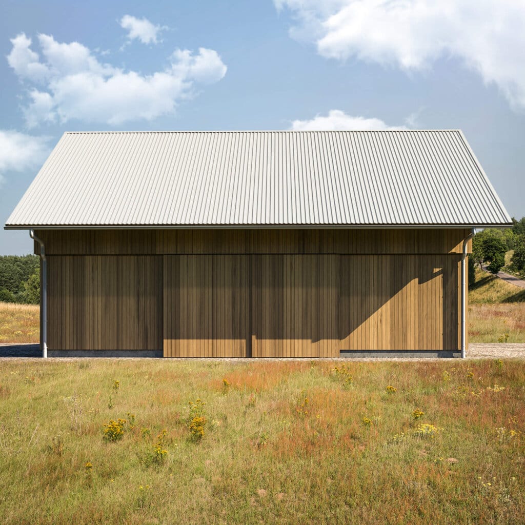 Scheune mit Fassade aus senkrecht verlegten Holzpaneelen und silbergrauem Dach aus Trapezblech, gelegen in einer offenen, naturbelassenen Wiesenlandschaft unter leicht bewölktem Himmel.