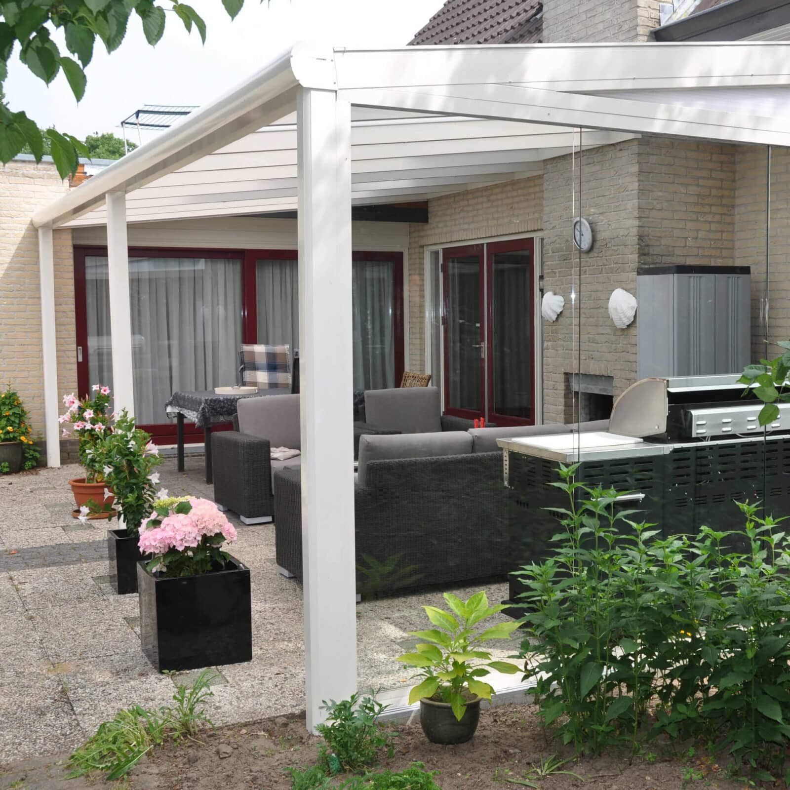 Weiße Terrassenüberdachung, darunter eine Sitzecke.