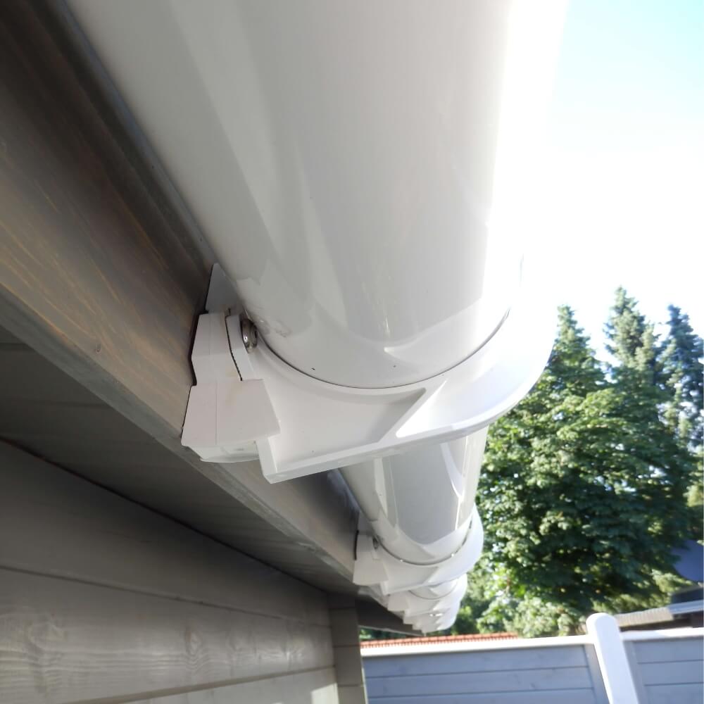 Montagedetail einer weißen Regenrinne am Haus, zeigt das Verbindungsstück und die Halterung