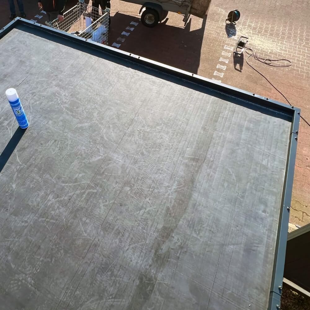 Hochwertige EPDM-Dachfolie auf Flachdach angebracht EPDM-Dachfolie professionell auf einem Flachdach verlegt, im Hintergrund Arbeitsmaterialien und Werkzeuge sichtbar